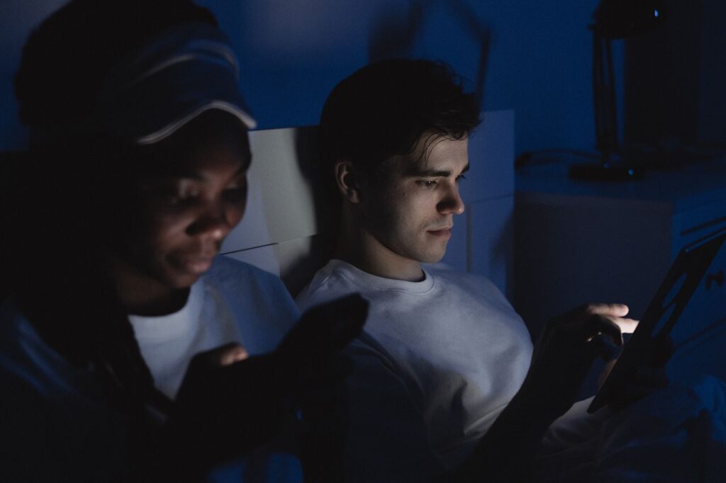 Couple using their phones in bed in the dark