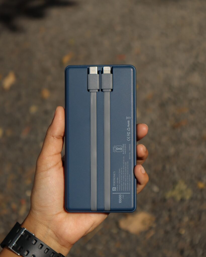 Hand holding a blue power bank with built-in cables