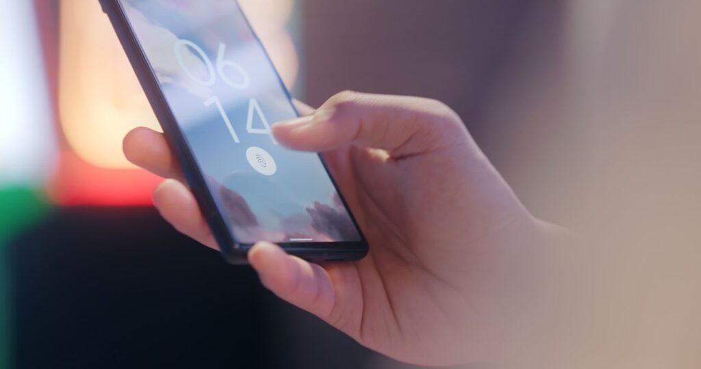 Hand holding a smartphone with a fingerprint lock screen