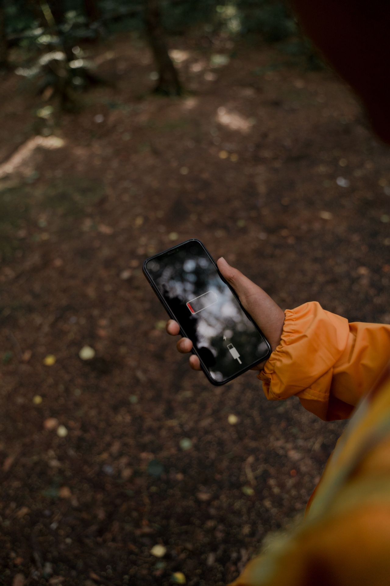 Hand holding a smartphone with a low battery warning outdoors