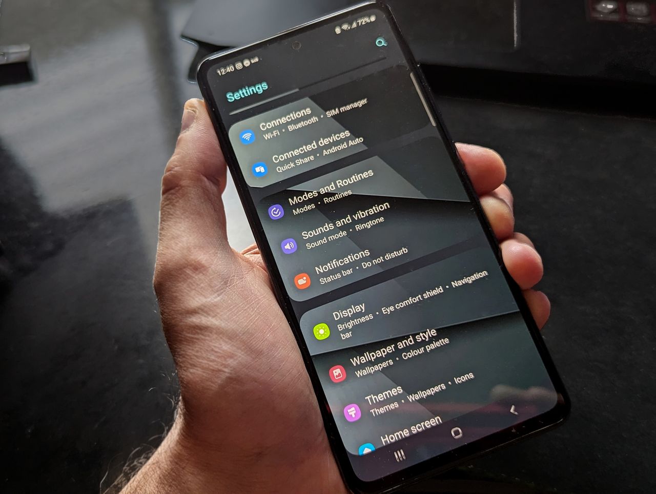 Hand holding an Android phone showing the settings screen