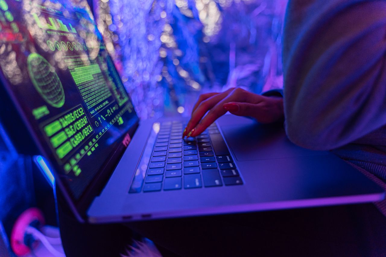 Hands typing on a laptop with security graphics on screen
