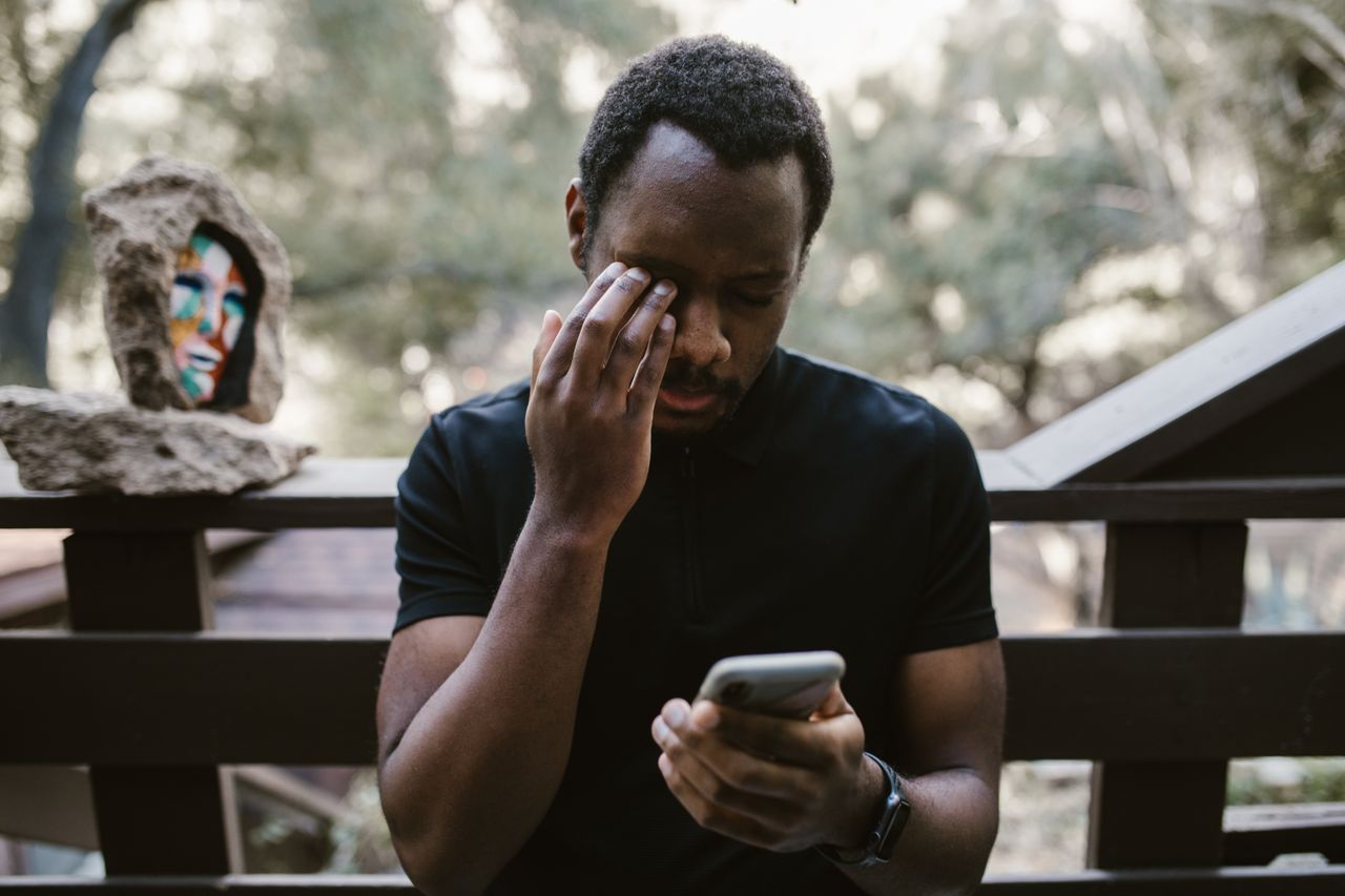 Man holding a smartphone and thinking on a balcony