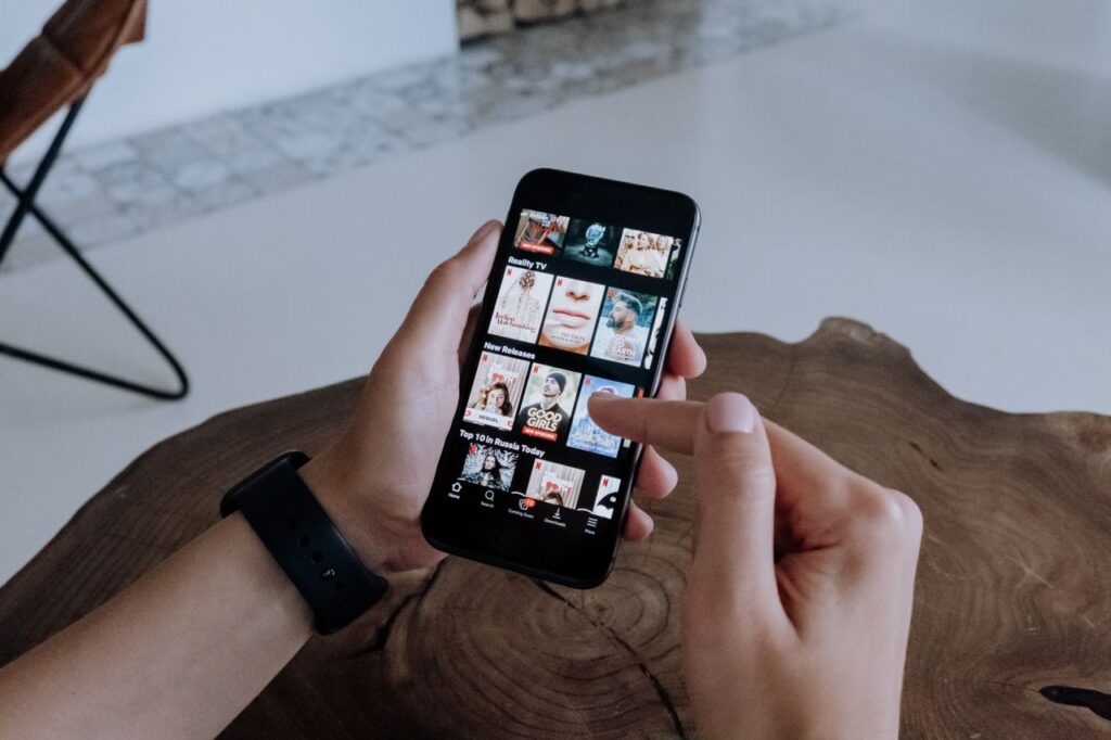 Person browsing apps on a smartphone at a wooden table