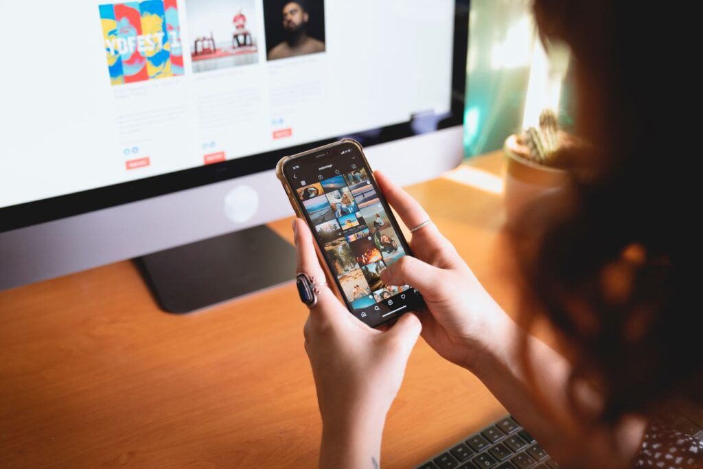 Person browsing images on a smartphone at a desk