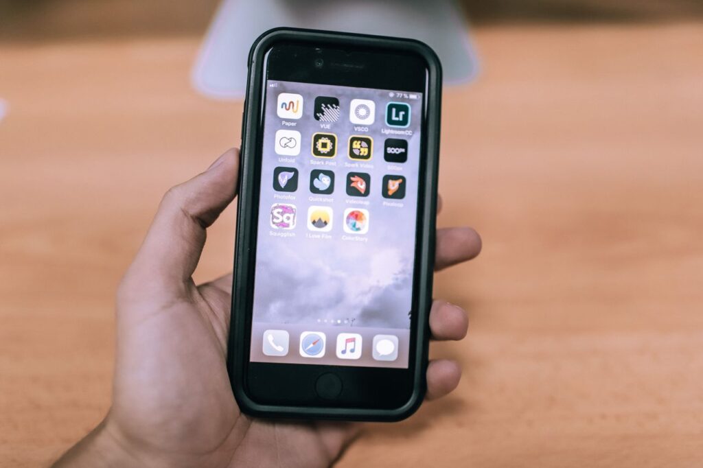 Person holding an iPhone displaying app icons