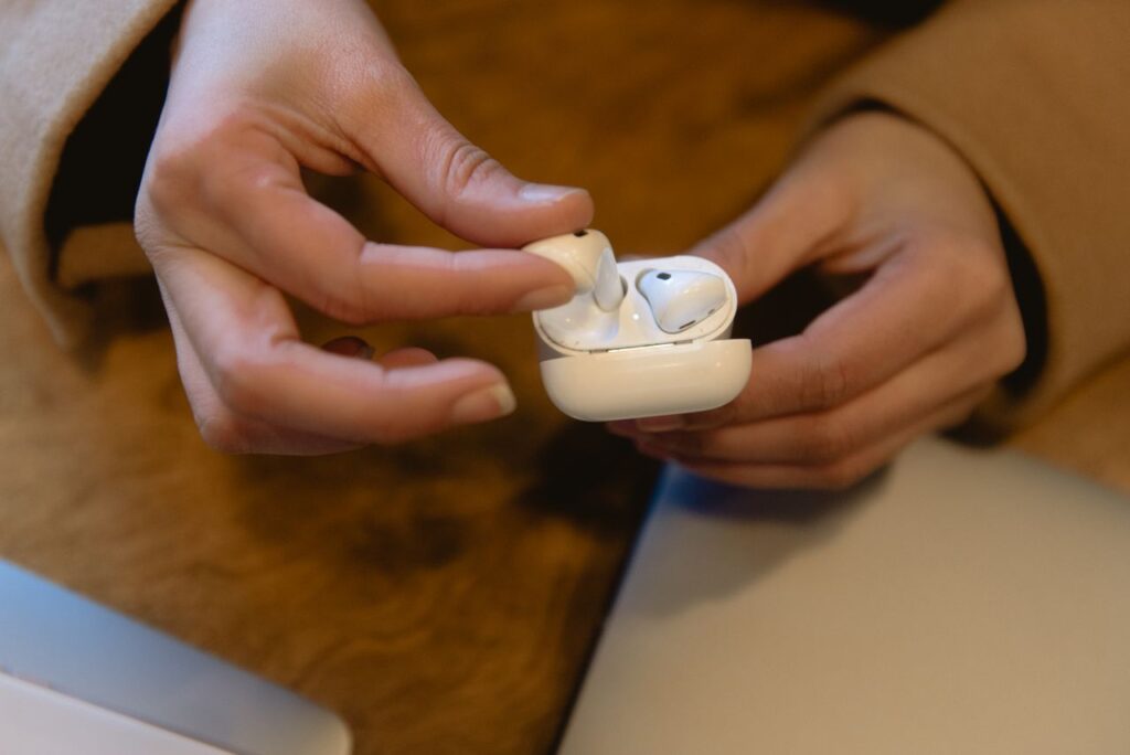 Person holding wireless earbuds