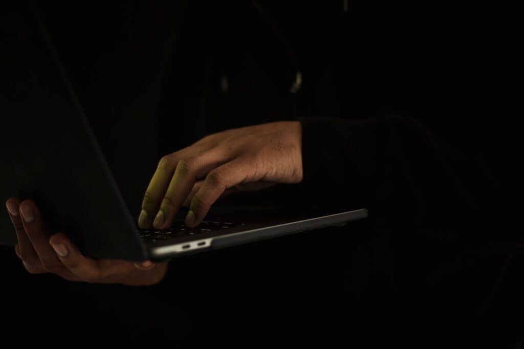 Person typing on a laptop in a dark room