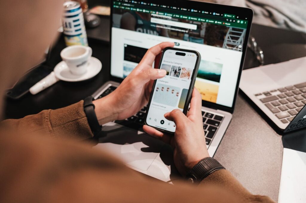 Person using a smartphone and laptop with coffee