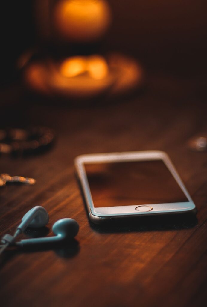 Phone with earphones on a wooden table in warm light