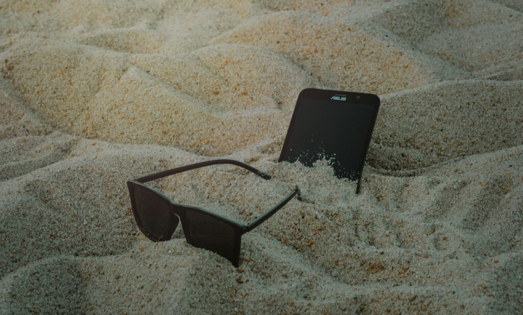Smartphone and sunglasses left on beach sand
