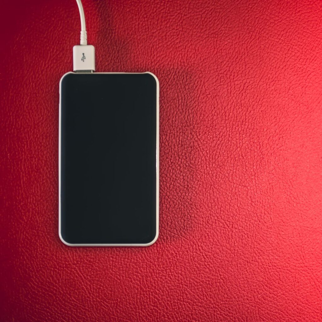 Smartphone connected to a charger on a leather surface