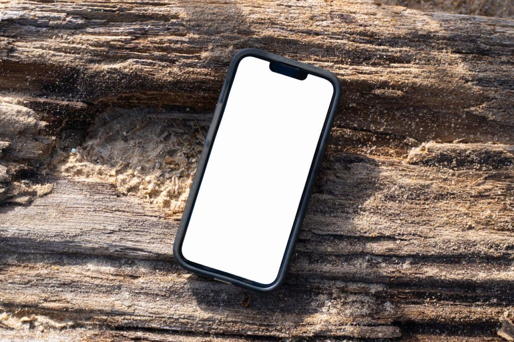 Smartphone with a blank screen on a sandy log at the beach