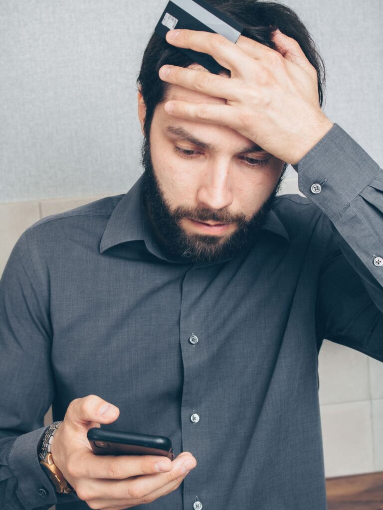 Stressed man holding a smartphone and a credit card