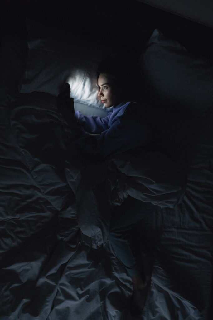 Woman lying in bed at night looking at her phone