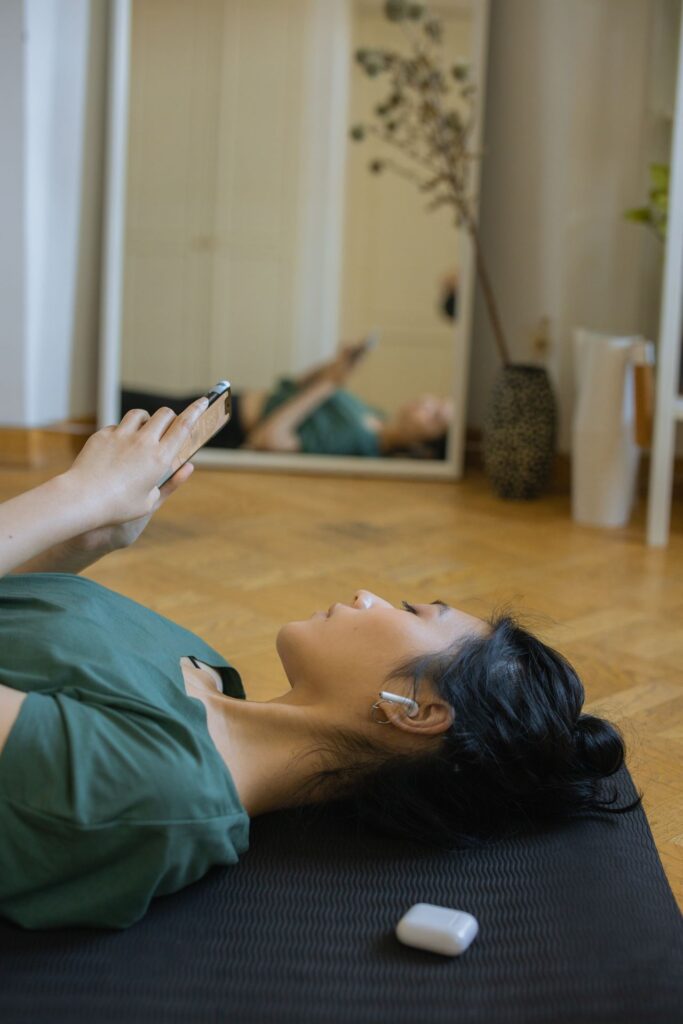Woman on a yoga mat listening to music with earbuds and a smartphone