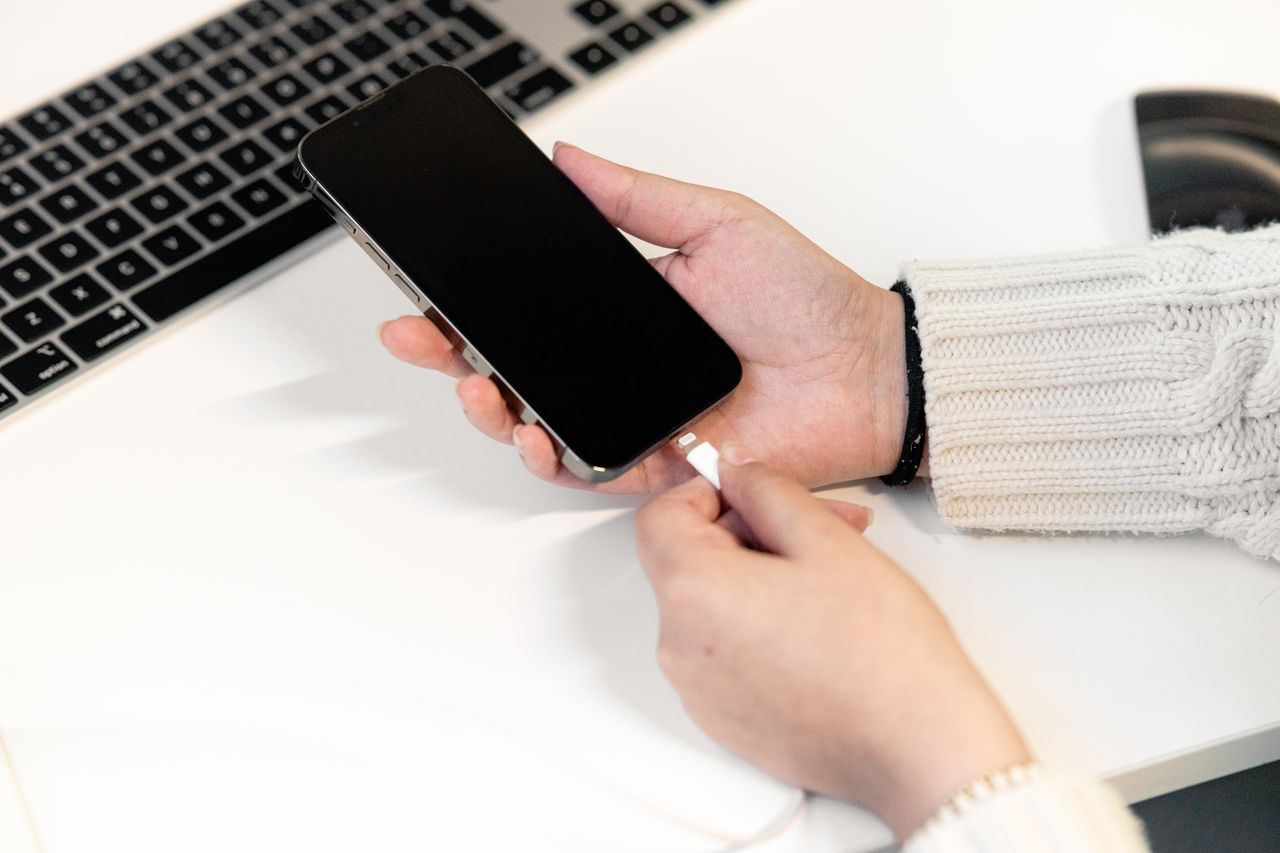 Woman plugging her smartphone into a charger at a desk