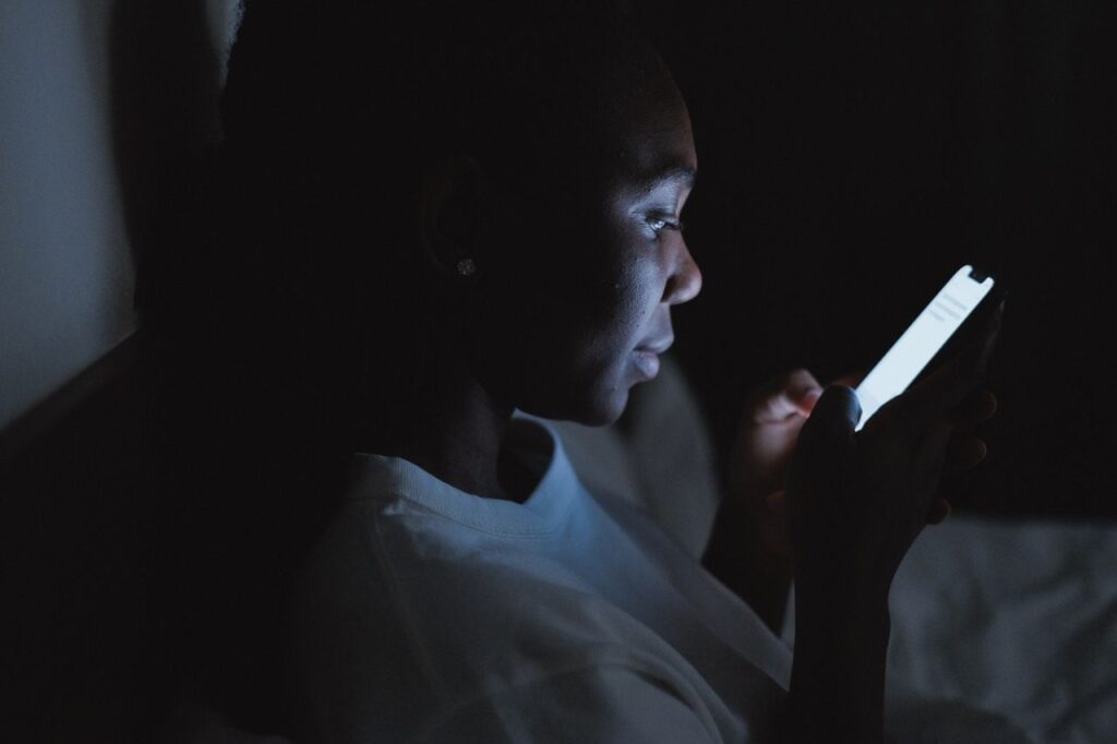 Woman using a smartphone in a dark bedroom