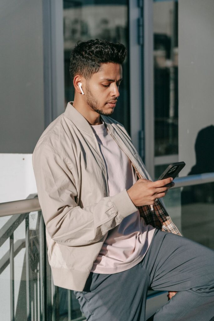 Young man with wireless earbuds using his phone on the street